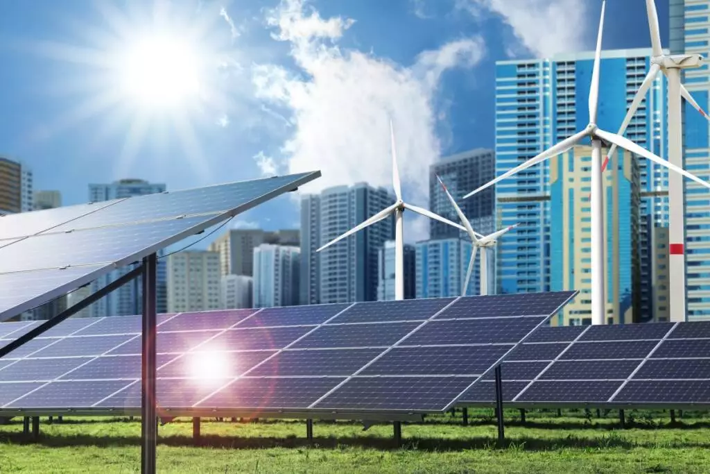 Daytime blue sky color outdoor photo of solar panels and wind turbines installed outdoors on green grass next to a large metropolitan city with multiple sky scrapers. Alternative energy source.