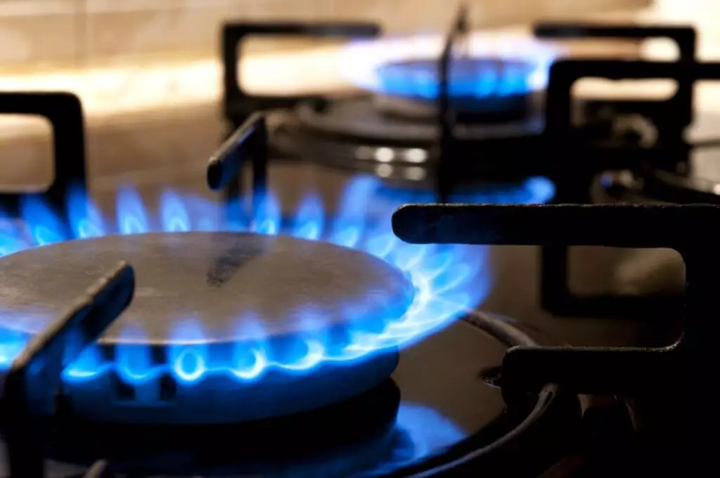 Color photo of a natural gas stove burners lit with blue flames.