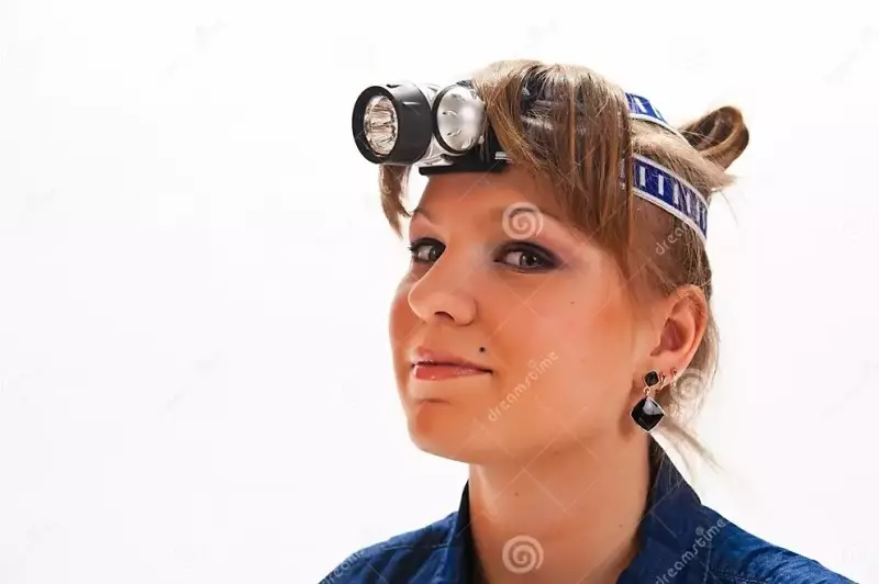 Color photo of a young white woman with red hair wearing a headlamp preparing for an emergency power outage on a white background.